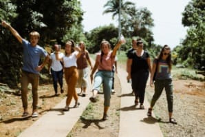 Group of young adults walking down path with hands raised