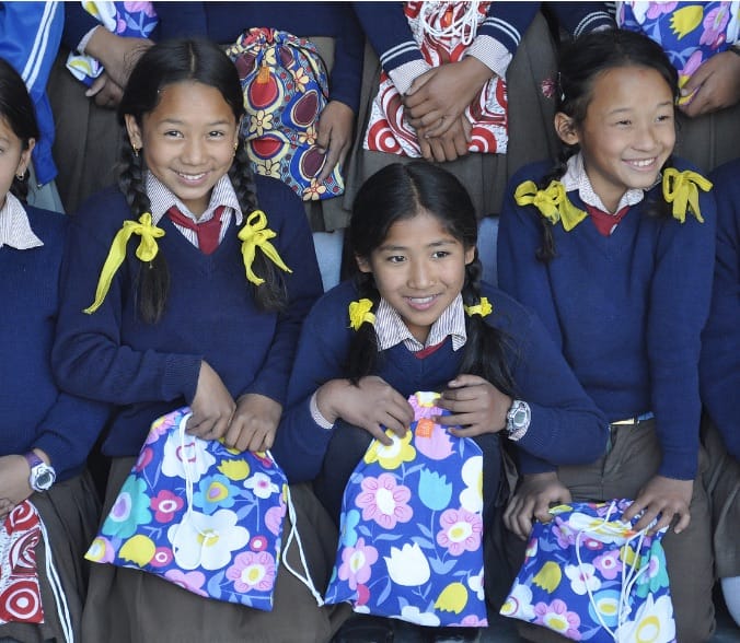 Group of smiling girls in matching uniform holding floral bags
