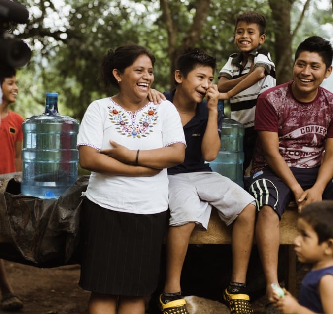 Family smiling seated next to 5-gallon water container